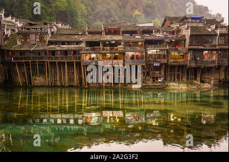 Hunan, Cina, 14 Nov 2011: vecchie case in equilibrio su pali di legno lungo il fiume. Foto Stock