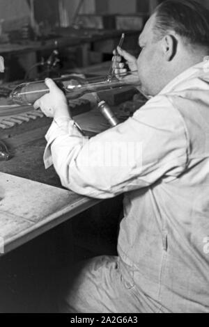 Ein Mitarbeiter einer Leuchtröhrenfabrik bei der Herstellung einer Leuchtöhre, Deutschland 1930er Jahre. Un membro dello staff di produzione di un tubo fluorescente, Germania 1930s. Foto Stock