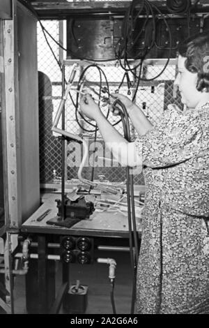 Eine Mitarbeiterin bei der Produktion von Leuchtröhren, Deutschland 1930er Jahre. Un personale femminile memmber produrre tubi fluorescenti, Germania 1930s. Foto Stock