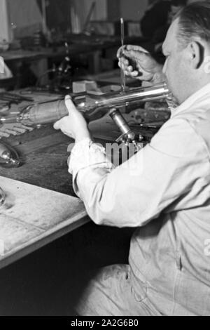 Ein Mitarbeiter einer Leuchtröhrenfabrik bei der Herstellung einer Leuchtöhre, Deutschland 1930er Jahre. Un membro dello staff di produzione di un tubo fluorescente, Germania 1930s. Foto Stock