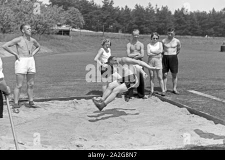 Übung im Weitsprung auf dem Sportplatz des KdF Sportheim Belzig in der Mark Brandenburg, Deutschland 1930er Jahre. Salto in lungo esercizio presso il campo sportivo dello sports club house a Belzig nel Brandeburgo, Germania 1930s. Foto Stock