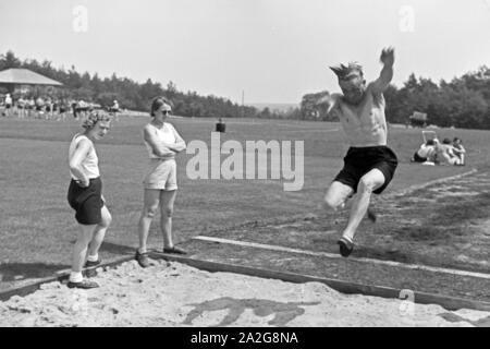 Übung im Weitsprung auf dem Sportplatz des KdF Sportheim Belzig in der Mark Brandenburg, Deutschland 1930er Jahre. Salto in lungo esercizio presso il campo sportivo dello sports club house a Belzig nel Brandeburgo, Germania 1930s. Foto Stock