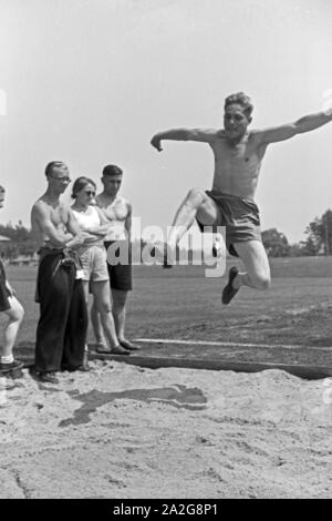 Übung im Weitsprung auf dem Sportplatz des KdF Sportheim Belzig in der Mark Brandenburg, Deutschland 1930er Jahre. Salto in lungo esercizio presso il campo sportivo dello sports club house a Belzig nel Brandeburgo, Germania 1930s. Foto Stock