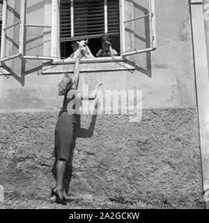 Eine junge Frau unterhält sich am Fenster Mit einem kleinen Jungen und seinem Hund, Deutschland 1930er Jahre. Una giovane donna con un ragazzo e il suo cane in una finestra, Germania 1930s. Foto Stock