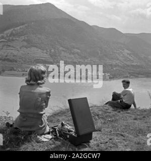 Eine junge Frau und ein junger Mann mit dem Electrola Koffer Grammofon und einer Electrole Schellackplatte, Österreich 1930er Jahre. Una giovane donna e un giovane uomo con un grammofono Electrola e un Electrola shellac record, Austria 1930s. Foto Stock