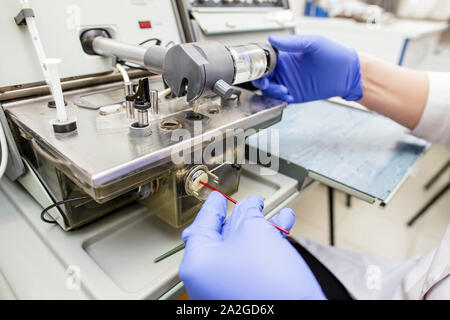 Un medico in blu guanti medici processi di esami del sangue per ossigeno su attrezzature di misurazione Foto Stock