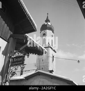 Blick in einen Ortskern mit Kirche und Ladenlokalen, Deutschland 1930er Jahre. vista di un centro citta' con la torre campanaria e una farmacia, Germania 1930s. Foto Stock