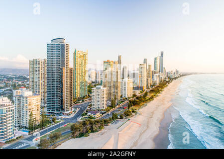 Antenna di sunrise skyline proprio sulla spiaggia. Bella la luce del mattino sulla Gold Coast holiday hotel destinazione dall'oceano. Foto Stock