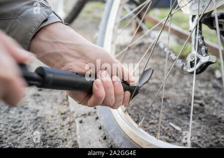 Voce maschile si gonfia la ruota di bicicletta con una pompa. Close-up Foto Stock