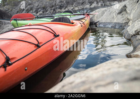 Due kayak stand ormeggiata su una spiaggia sassosa, sullo sfondo di una scogliera. Foto Stock