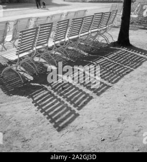 Stühle werfen ihren Schatten in der Sonne di Bad Salzuflen, Deutschland 1930er Jahre. Sedie e la loro ombra nel sole a Bad Salzuflen i giardini del centro termale, Germania 1930s. Foto Stock