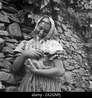 Eine junge Frau spielt in einem Weinberg mit einer Katze, Österreich 1930er Jahre. Una giovane donna che gioca con un gatto in un vigneto, Austria 1930s. Foto Stock