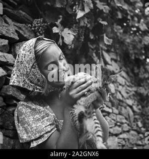 Eine junge Frau spielt in einem Weinberg mit einer Katze, Österreich 1930er Jahre. Una giovane donna che gioca con un gatto in un vigneto, Austria 1930s. Foto Stock