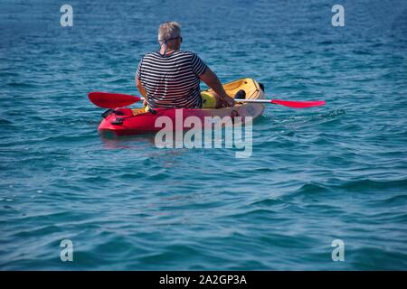 Vista posteriore del senior man paddling in kayak sul mare adriatico Foto Stock