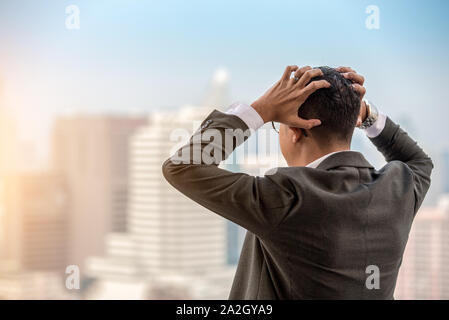 Sottolineato imprenditore con testa in mani nel suo ufficio Foto Stock