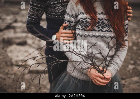 Islandese tradizionale look d'autunno. Maglia fatti a mano grigio e blu maglioni sulla donna e uomo giovane. Ramo concettuale bouquet. Foto Stock