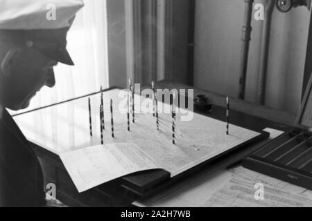 Mitarbeiter der Wetterdienststelle beim Sichten von Landkarten, Deutschland 1930er Jahre. Membro del personale di un ufficio meteorologico lavora con mappe, Germania 1930s. Foto Stock