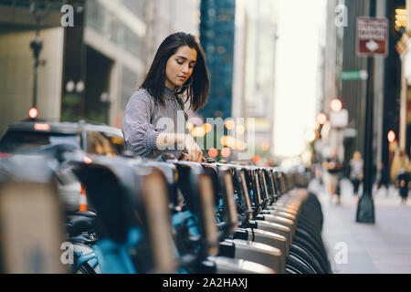 Ragazza affittare una bici da città da una bicicletta stand in Chicago Foto Stock