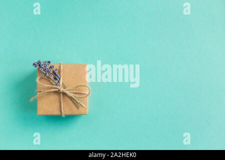 Craft confezione regalo con piccoli bouquet di lavanda su sfondo turchese. Vacanza eco-friendly concetto. Posto per il testo. Lay piatto. Foto Stock