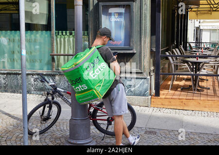 Polen Wroclaw Uber mangia il driver su una bici in attesa per il cibo alla ricerca sul suo cellulare 8-8-2019 foto Jaco Klamer Foto Stock