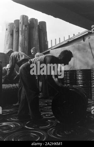 Lagerarbeiter der Rhenania Ossag Mineralölwerke AG DI AMBURGO das verladen Bitumenprodukt Mexphalt auf Schiffe, Deutschland 1930er Jahre. Warehousemen della Rhenania Ossag Mineraloelwerke AG ad Amburgo il carico di una nave con il bitume prodotto Mexphalt, Germania 1930s. Foto Stock