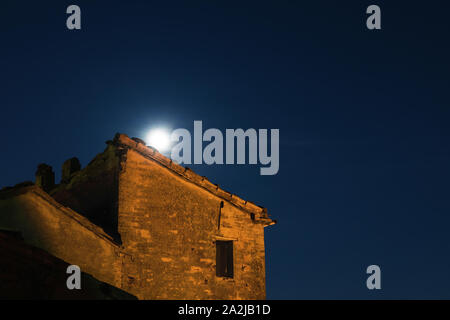 La luna sorge alle spalle di un antico edificio in rovina, Vista notte Foto Stock