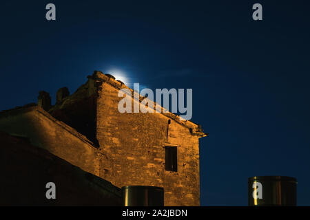 La luna sorge alle spalle di un antico edificio in rovina, Vista notte Foto Stock