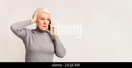 La donna in questione parlando al telefono, tenendo la mano sulla testa Foto Stock