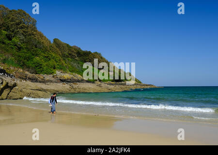 Donna che cammina lungo Carbis Bay beach in Cornovaglia Foto Stock