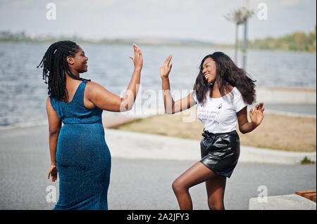 Due americano africano pelle scura amici femmina. Uno di loro più dimensioni modello, secondo slim. Divertirsi e trascorrere del tempo insieme. Dare alta cinque ciascuno Foto Stock