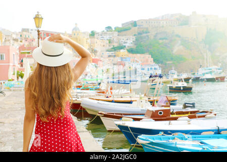 Vacanze in Italia. Vista posteriore della bella ragazza in un sorprendente coloratissimo porto di Procida in Italia. Foto Stock