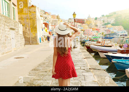 Vacanze in Italia. Vista posteriore della bella ragazza in un sorprendente coloratissimo porto di Procida in Italia. Foto Stock