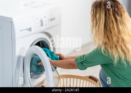 Giovane donna, il carico della macchina di lavaggio per la pulizia laundrys . Foto Stock