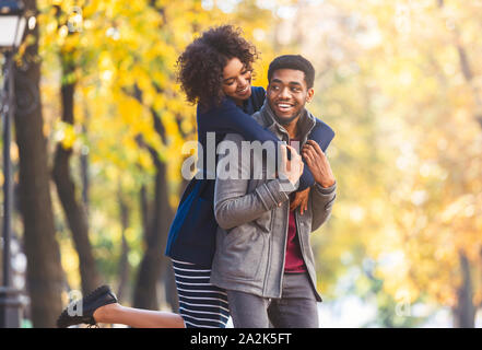 Carino nero ragazza saltato divertimento sul retro di guy Foto Stock