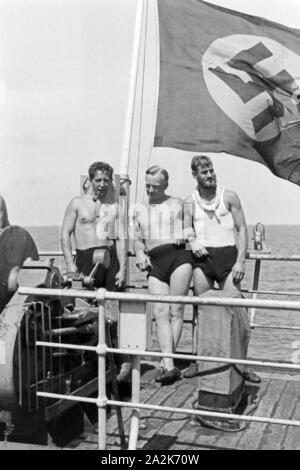 Drei Männer der Besatzung des Walfangfabrikschiffs 'Jan Wellem' unter der Reichsflagge am ontrollare des Schiffs, 1930er Jahre. Tre membri dell equipaggio della nave facotry 'Jan Wellem' sotto la bandiera a poppa della nave, 1930s. Foto Stock