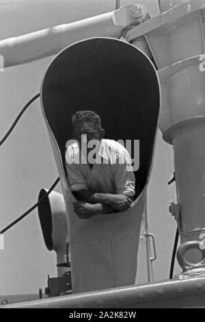 Ein Mann der Besatzung des Fabrikschiffs 'Jan Wellem' schaut aus einem der Belüftungsrohre auf Deck, 1930er Jahre. Un membro di equipaggio guardando fuori di uno dei tubi aria condizionata sul ponte, 1930s. Foto Stock