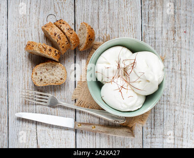 Formaggio italiano burrata con il pane su un sfondo di legno Foto Stock