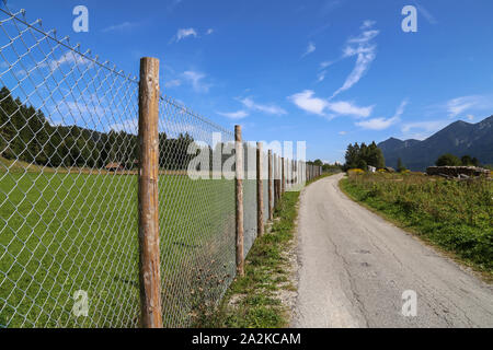 Rete metallica recinzione lungo la strada di campo Foto Stock