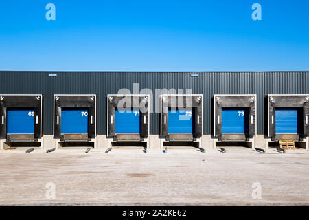 Fila di banchine di carico con porte a serranda in corrispondenza di un magazzino industriale. Foto Stock