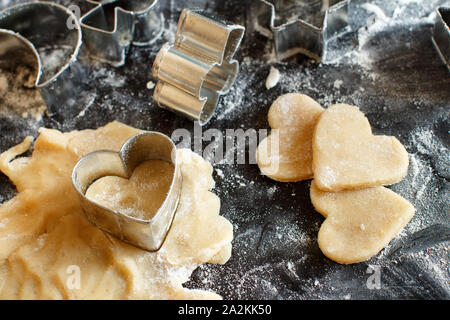 Close up di cookie cutter in un impasto al buio su un tavolo Foto Stock