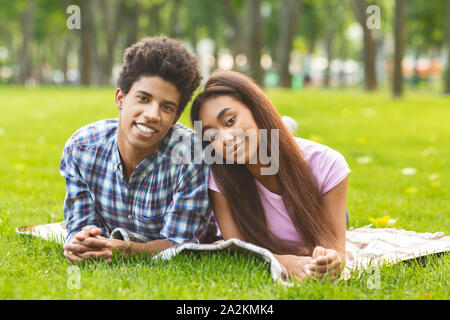 Coppia felice in amore godendo giorno insieme, giacente su plaid in posizione di parcheggio Foto Stock