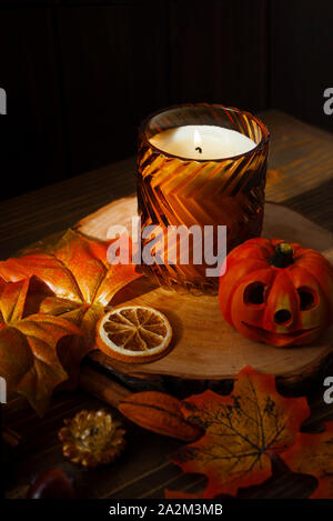 Colorato moody vista autunnale di home decor con candela, foglie e frutta secca su rustiche superficie di legno. Foto Stock