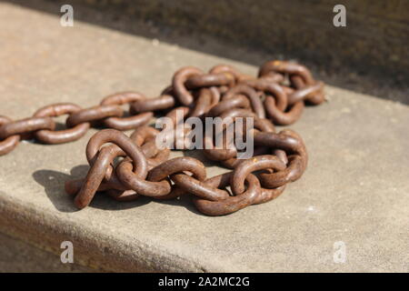 Un arrugginito maglia di catena su un gradino di pietra. Foto Stock