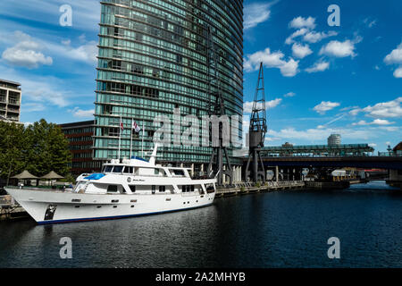 Un lussuoso yacht ormeggiati nel fluviale del Canary Wharf di Londra, con l'alto edificio aziendale in background Foto Stock