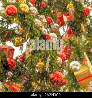 Acquerello immagine: magnifico albero di Natale decorato con argento e palle rosse e pacchi avvolti in carta da imballaggio, vista da vicino Foto Stock