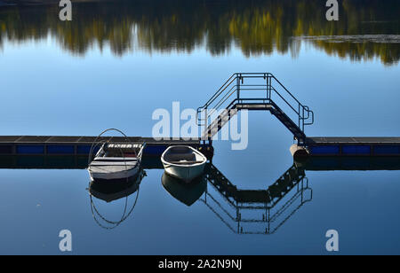 Paesaggio autunnale. Un lago, un ponte di barche e due barche. In autunno gli alberi si riflette nel lago. 68782 Bruehl, Baden-Wuerttemberg (Germania). Foto Stock