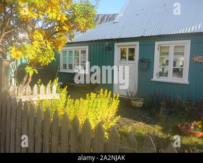 Un vivacemente colorato turchese casa tradizionale con un recinto di picchetti bianchi su una soleggiata giornata autunnale in Isafjordur, Westfjords, Islanda Foto Stock