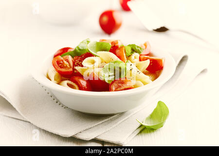 Insalata di pasta con pomodori ciliegia, spezie e le foglie di basilico. Cibi fatti in casa. Foto Stock