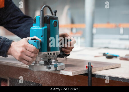 Produzione di mobili artigianali o concetto: lavoratore la lucidatura della superficie di legno dei mobili parte con macchina polacco Foto Stock