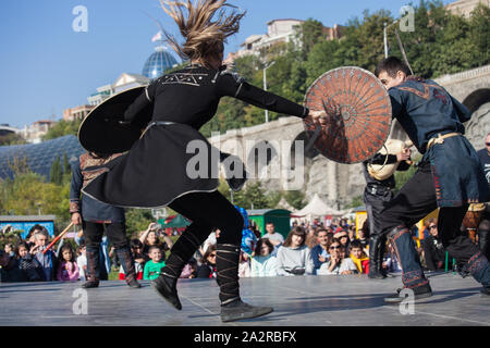 La Georgia, Tbilisi-07 Ottobre 2017: guerrieri vestiti in stile georgiano costumi nazionali tenere coltelli, spade e scudi e lotta su Tbilisoba vacanza. Octob Foto Stock